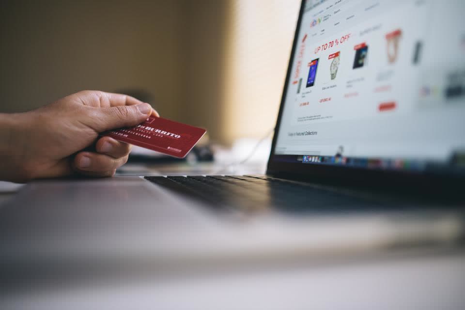 Persona hace una compra en línea con su tarjeta frente a una tienda virtual